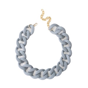 Puede incluir: Un collar de cadena gris grueso con un cierre dorado. El collar está hecho de un material grueso parecido al caucho.