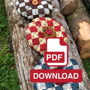 May include: Three round, quilted fabric pincushions in red, white, and blue with a checkered pattern. The pincushions are sitting on a log. A red button is visible on the middle pincushion. A white PDF icon with the word "PDF" in red is on top of the pincushions. A red button with the word "DOWNLOAD" is below the PDF icon.