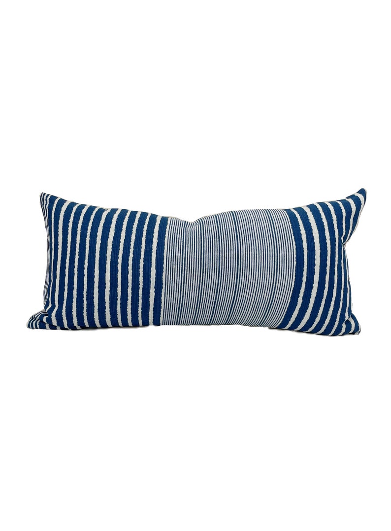 May include: A rectangular decorative pillow with a blue and white striped pattern. The pillow has vertical stripes on the left and right sides, and horizontal stripes in the center. The pillow is a long, lumbar style.