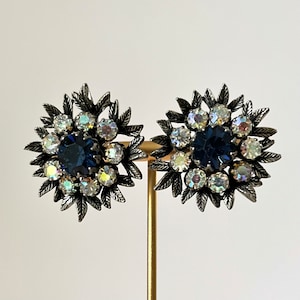 Könnte beinhalten: Ein Paar silberfarbene Ohrringe mit einem Cluster aus klaren und blauen Strasssteinen in einem floralen Design.