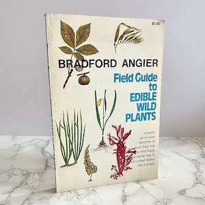 Può includere: Una guida sul campo vintage intitolata "Field Guide to Edible Wild Plants" di Bradford Angier. La copertina presenta illustrazioni di varie piante in verde, marrone e rosso, con il prezzo di $5,95 in alto a destra.