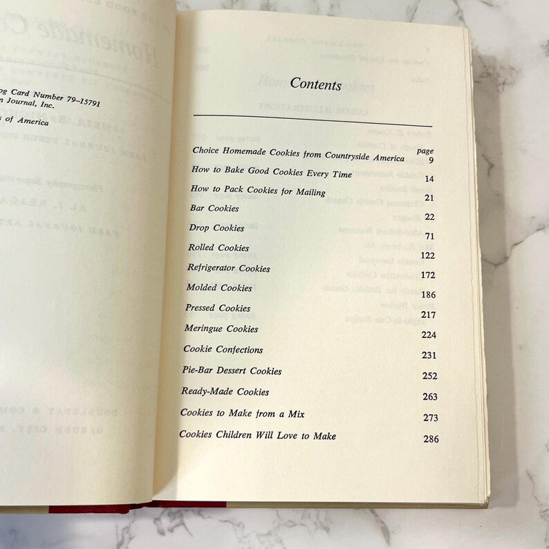 K&ouml;nnte beinhalten: Ein Buch mit dem Titel "Choice Homemade Cookies from Countryside America" mit einem Inhaltsverzeichnis, das verschiedene Arten von Keksen und die Seitenzahlen auflistet, auf denen sie zu finden sind.