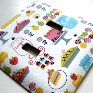 May include: White light switch cover with a colorful pattern of pies, cakes, and other sweet treats. The text "Sugar" and "Butter" are visible on the cover.