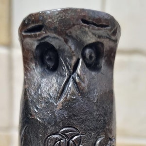 以下が含まれることがあります： 詳細な彫刻が施された黒い金属製のフクロウの彫刻。フクロウは枝に止まっており、翼を広げています。