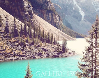 May include: A turquoise blue lake surrounded by snow-capped mountains and evergreen trees. The text "GALLERY 13" is visible in the water.