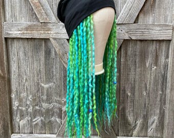 Peut inclure: Un bonnet noir avec de longues dreadlocks vertes et bleues vibrantes. Les dreadlocks sont un mélange de vert vif et de turquoise, avec quelques petites perles bleues. Le chapeau est fait d'un tissu sombre et doux.