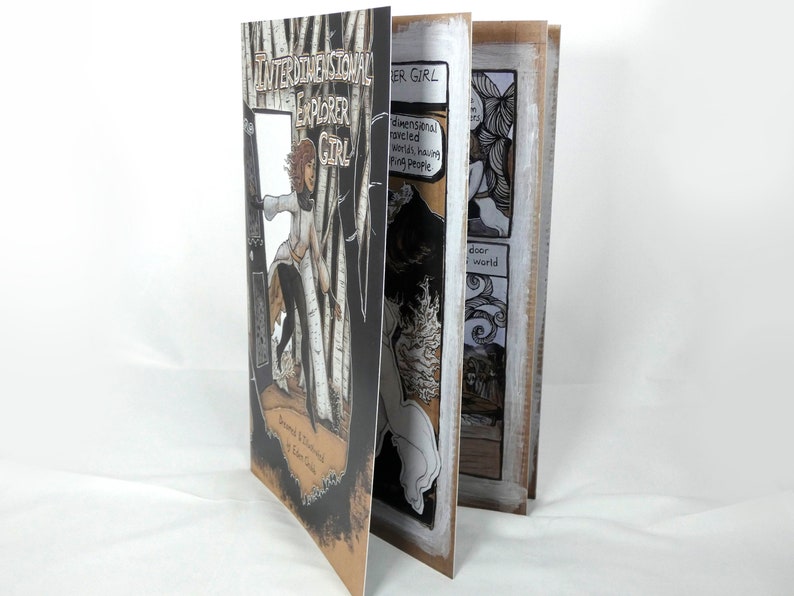 May include: A black and white comic book titled "Interdimensional Explorer Girl" with a drawing of a girl in a white shirt and black trousers standing in a forest. The book is open to a page with a drawing of a girl in a white dress standing in a forest.