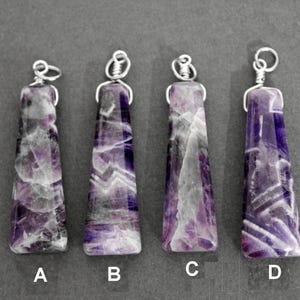 May include: Four amethyst pendants with silver wire loops. The pendants are all different shapes and sizes, but they all have a similar purple and white color scheme.