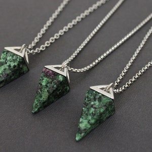 May include: Three necklaces with triangular pendants. Each pendant is made of green and red speckled stone, set in a silver-colored metal frame, and hangs from a delicate chain. The pendants have a geometric shape.