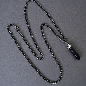 May include: A black chain necklace with a black crystal pendant. The pendant has a silver setting.