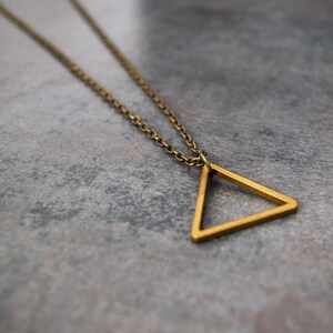 Peut inclure: Un collier en cha&icirc;ne dor&eacute;e avec un pendentif en forme de triangle simple.