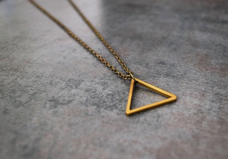 Peut inclure: Un collier en cha&icirc;ne dor&eacute;e avec un pendentif en forme de triangle simple.