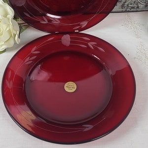 May include: Two red glass dinner plates with a white etched design. The plates are stacked on top of each other.