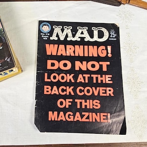 May include: A vintage MAD Magazine cover with a black background and bold orange text that reads "WARNING! DO NOT LOOK AT THE BACK COVER OF THIS MAGAZINE!". The magazine is labeled "No. 73 Sept. '62" and has a price of 25 cents.