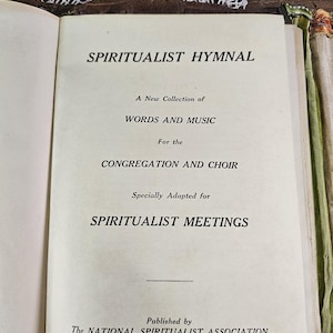May include: Open book titled "SPIRITUALIST HYMNAL" with text: "A New Collection of WORDS AND MUSIC for the CONGREGATION AND CHOIR." Published by The NATIONAL SPIRITUALIST ASSOCIATION of the United States of America.