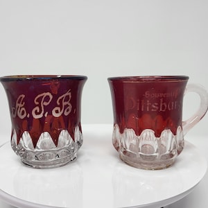 May include: Two red glass cups, one with the inscription "A.P.B." and the other with the inscription "Souvenir Dillsburg".