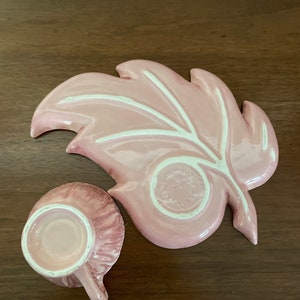 Pu&ograve; includere: Un set da t&egrave; in ceramica rosa con un design a foglia. Il piattino ha la forma di una foglia con un motivo di venature bianche. La tazza da t&egrave; ha un motivo a spirale rosa e bianco.