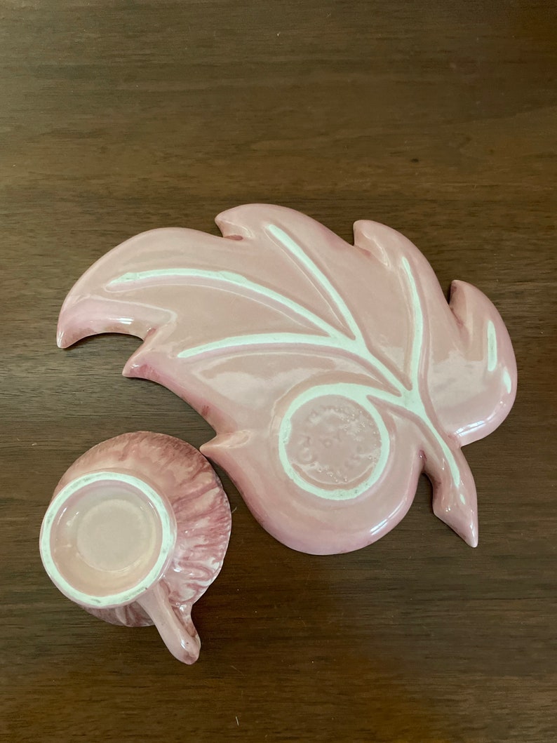 Pu&ograve; includere: Un set da t&egrave; in ceramica rosa con un design a foglia. Il piattino ha la forma di una foglia con un motivo di venature bianche. La tazza da t&egrave; ha un motivo a spirale rosa e bianco.