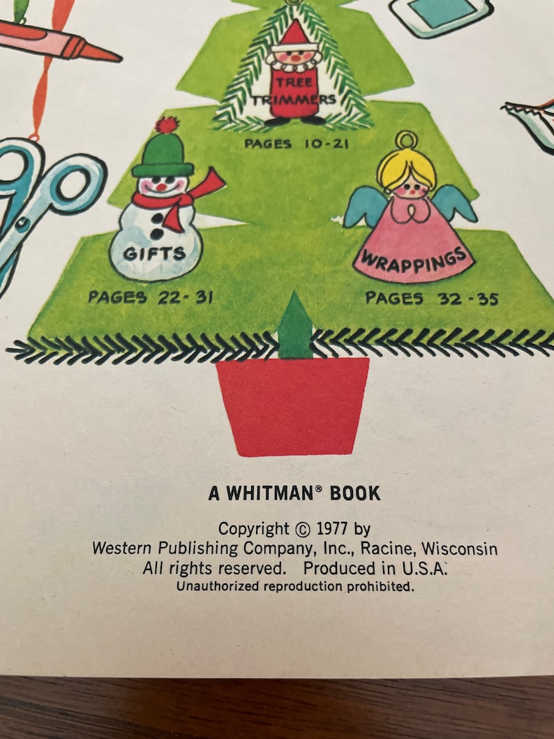 Peut inclure: Un livre de bricolage de No&euml;l vintage avec un sapin de No&euml;l vert sur la couverture. L'arbre est d&eacute;cor&eacute; d'ornements en papier, dont un bonhomme de neige, un ange et un P&egrave;re No&euml;l. Le titre du livre est "A Whitman&reg; Book" et la date de copyright est 1977.