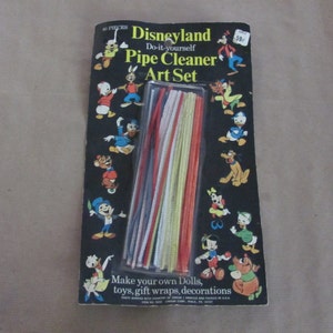 May include: A package of 40 colorful pipe cleaners with a Disneyland theme. The package features a black background with various Disney characters, including Mickey Mouse, Donald Duck, Goofy, and Pluto. The text on the package reads "Disneyland Do-it-yourself Pipe Cleaner Art Set".