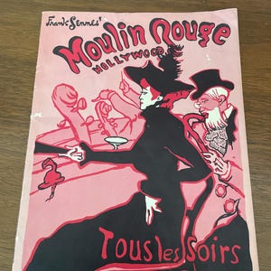 May include: A vintage poster with a pink background features the words "Moulin Rouge Hollywood" in red. The poster depicts a woman in a black dress and hat, with a man in a tuxedo. The text "Tous les Soirs" is also visible.