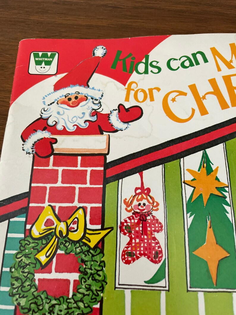 Peut inclure: Une couverture de livre pour enfants vintage avec une illustration rouge et blanche du P&egrave;re No&euml;l qui regarde par une chemin&eacute;e. Le titre du livre est "Kids can Make for Christmas" en lettres vertes et orange.