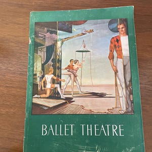 May include: A vintage book cover with the title "BALLET THEATRE" in white letters on a green background. The cover features a colorful illustration of ballet dancers on a stage, with a surrealist figure on the right.