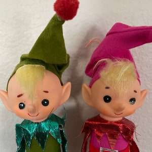 May include: Two vintage felt Christmas elves with green and pink hats, blonde yarn hair, and sparkly green and red collars.