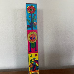 May include: A colorful, stacked, wooden toy with a flower, a face, and a person riding a horse. The toy is made of wood and has a bright, cheerful design.