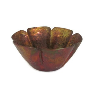 May include: A small, copper bowl with a hammered finish. The bowl is shaped like a flower with five petals and has a reddish-brown patina.