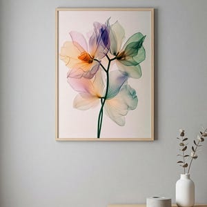 May include: A framed floral art print featuring a delicate botanical illustration. The artwork showcases translucent flowers in shades of orange, pink, purple, and green against a light background. The frame is made of light-colored wood.