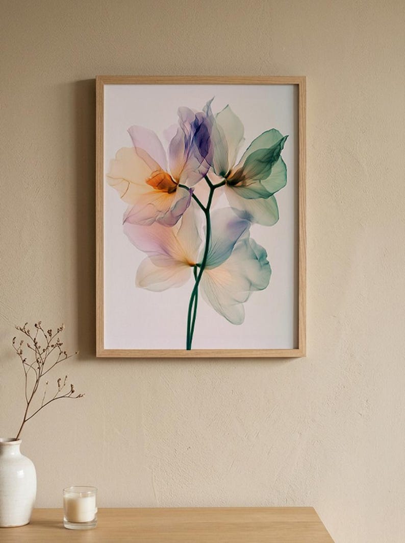 May include: A framed floral print featuring a close-up of translucent flowers in shades of peach, purple, and green. The artwork is set against a white background and framed in light wood. The image is mounted on a beige wall.