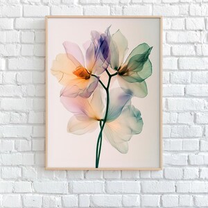 May include: A framed print featuring a close-up of translucent flowers in shades of orange, pink, purple, and green. The delicate petals are arranged on a dark green stem. The artwork is displayed against a white background.