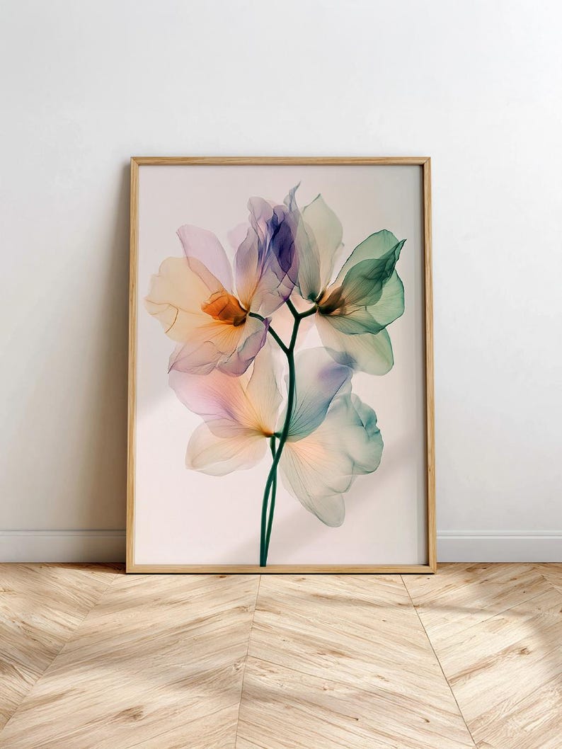 May include: A framed art print featuring a close-up of delicate, translucent flowers in shades of peach, purple, and green. The botanical illustration is set against a soft, neutral background, encased in a light wood frame.