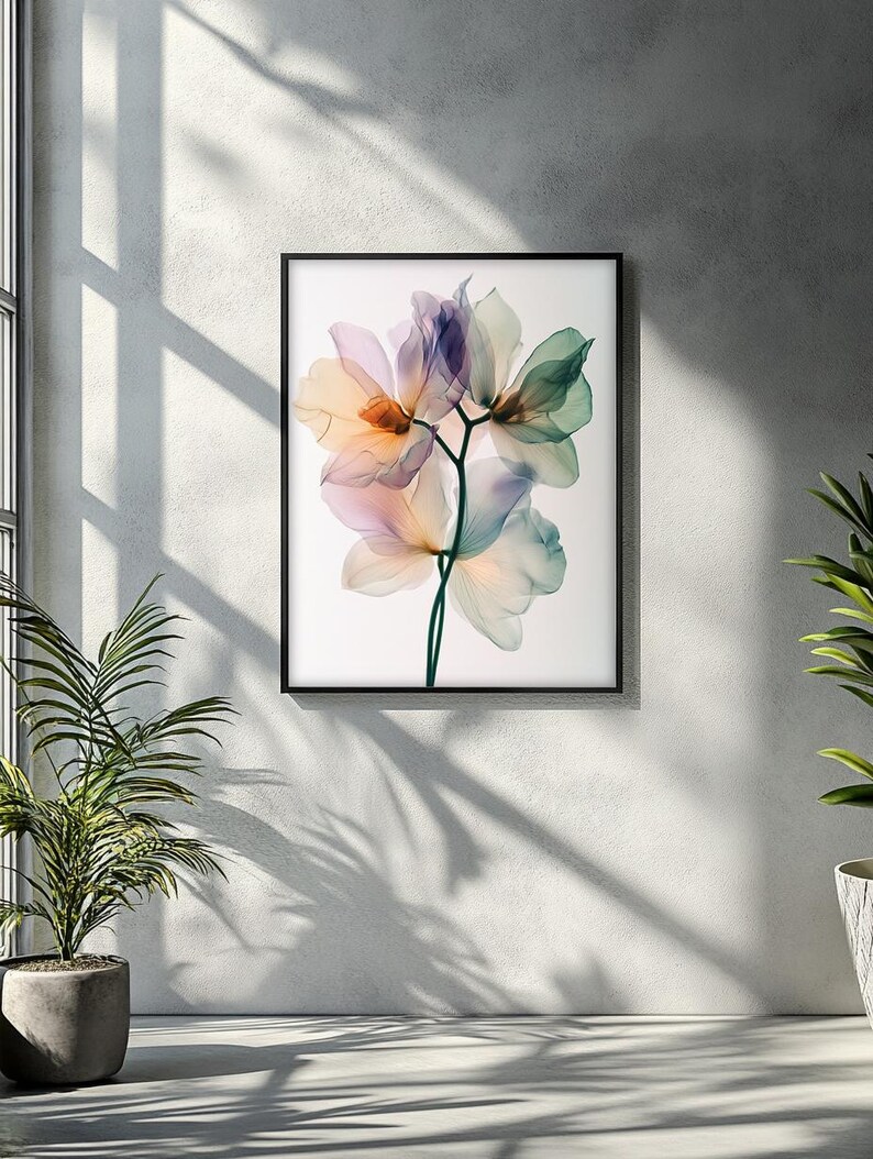 May include: A framed art print featuring a close-up of delicate, translucent flowers in shades of peach, lavender, and green. The floral arrangement is set against a white background, encased in a black frame, and mounted on a textured wall.