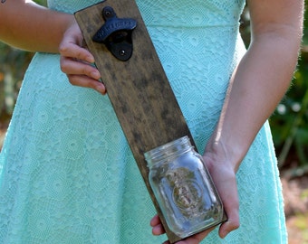 Peut inclure: Un ouvre-bouteille mural en bois avec un bocal en verre attaché. L'ouvre-bouteille porte l'inscription "Drink Here".