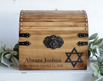 May include: A wooden chest with a brass latch and hinges. The chest is decorated with a Star of David and the text "Abram Joshua Bar Mitzvah October 15, 2023".
