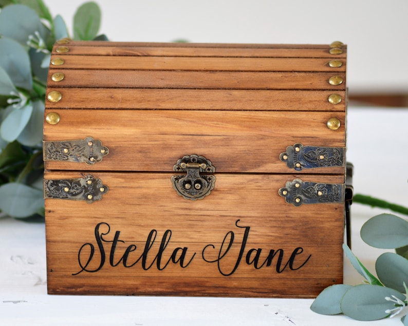 May include: A wooden treasure chest with a hinged lid, brass accents, and the name "Stella Jane" engraved on the front.