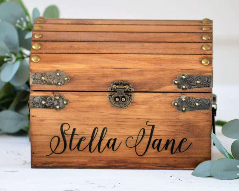 May include: A wooden treasure chest with a hinged lid, brass accents, and the name "Stella Jane" engraved on the front.