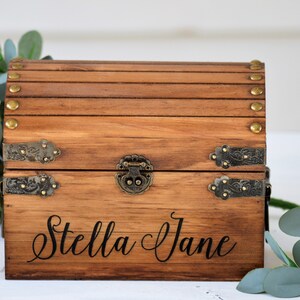 May include: A wooden treasure chest with brass accents and a personalized inscription that reads "Stella Jane".
