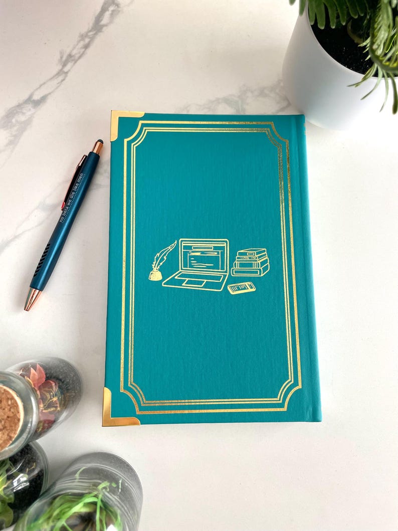 Peut inclure: Journal &agrave; couverture rigide bleu turquoise avec des accents dor&eacute;s et une illustration dor&eacute;e d'un ordinateur portable, de livres et d'un stylo sur la couverture.