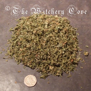 May include: A pile of dried, chopped green herbs, possibly for culinary or ritual use, with a twenty pence coin for scale. The herbs are a mix of green and brown, with a rough, textured appearance. The text "The Witchery Cove" is in the upper left corner.