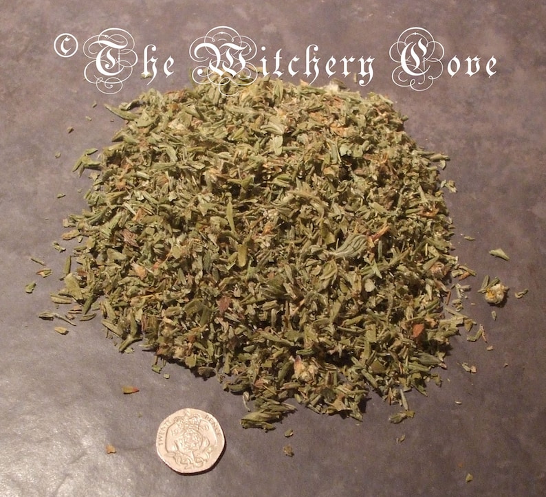 May include: A pile of dried, chopped green herbs, possibly for culinary or ritual use, with a twenty pence coin for scale. The herbs are a mix of green and brown, with a rough, textured appearance. The text "The Witchery Cove" is in the upper left corner.