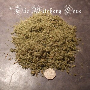 May include: A pile of dried, green herbs with a coin for scale. The herbs are finely chopped and appear to be a mix of leaves and stems. The text "The Witchery Cove" is in the upper left corner.