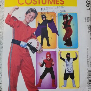 May include: A sewing pattern for boys' costumes. The pattern includes five different costumes: a superhero, a ninja, a bat, a red superhero, and a white ninja. The pattern is for sizes 7-14.