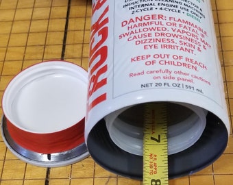 May include: A white can with a red label that says "Truck Stop" and instructions for using the product in gas and diesel engines. The can is open and a yellow measuring tape is next to it.