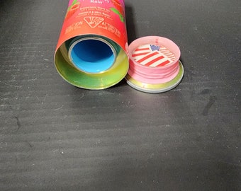 May include: A pink and red can with the words "Skintimale Raspberry Rain" and a graphic of a raspberry. The can is open and the lid is off. The lid has a red, white, and blue design.