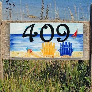 Beach house number plaque hand painted yellow and blue chair with red boat and a red pail.