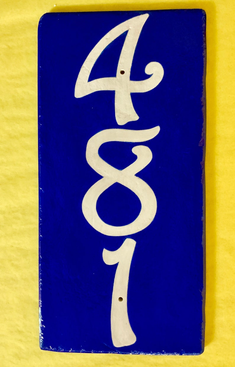 May include: A blue ceramic tile with the number 481 painted in white. The tile is a house number.