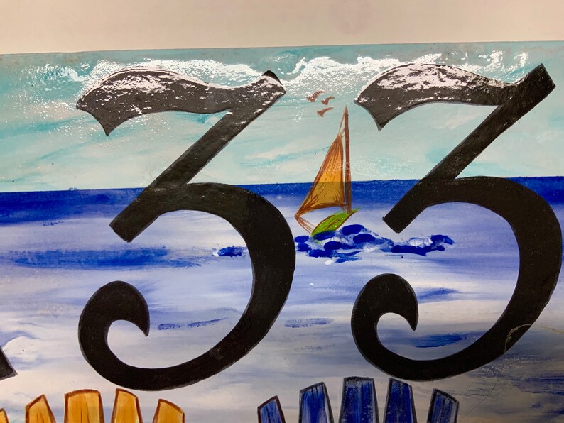 May include: A hand-painted house number sign with the number "33" in black. The background is a blue and white watercolor painting of a seascape with a sailboat.